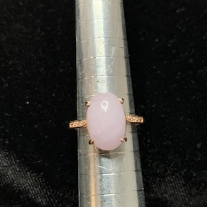 May include: A rose gold ring with a light purple oval gemstone and a row of small clear gemstones around the band.