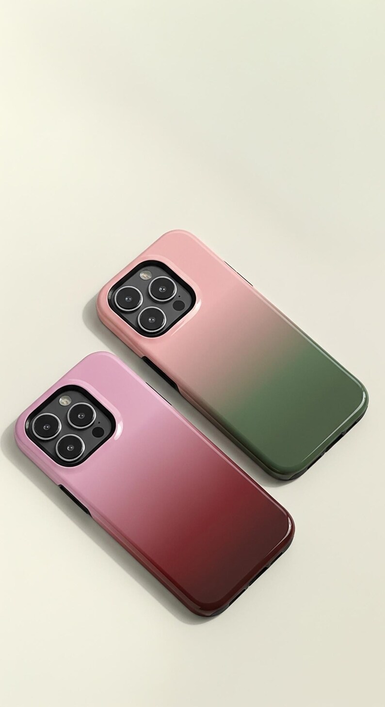 May include: Two smartphone cases with a gradient design. One case transitions from pink to green, and the other from pink to burgundy. Both cases have a glossy finish and a black border around the camera.