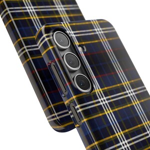 May include: A black phone case with a blue, yellow, and red plaid pattern. The case has a raised camera bump with three lenses.