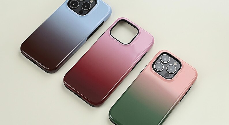 May include: Three smartphone cases in a gradient color scheme. The cases are in shades of blue to brown, pink to red, and pink to green. The cases have a glossy finish and a camera cutout.