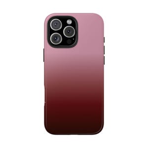 May include: A gradient phone case in shades of pink and burgundy. The case has a glossy finish and a camera cutout with multiple lenses. The design transitions from light pink at the top to a deep burgundy at the bottom.