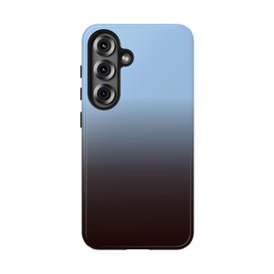 May include: A smartphone case with a gradient design. The case transitions from light blue at the top to dark brown at the bottom. It features a camera module with three lenses and a flash.