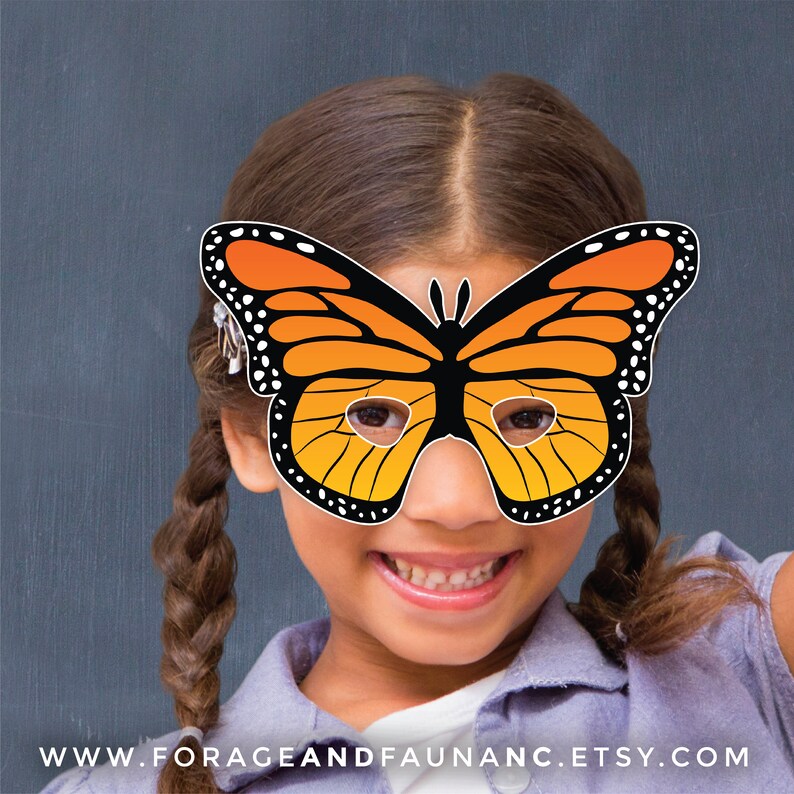 May include: A child wearing a paper butterfly mask with orange and black wings. The mask has eye holes and is held in place with a string. The child is smiling and has brown hair.