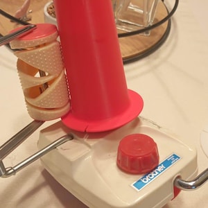 May include: A white yarn winder with a red yarn holder and a red knob. The winder is labeled "brother" and "made in japan".