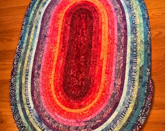 Alfombra ovalada de algodón batik vibrante (42,5" x 29"): tonos de morado, rojo, naranja y azul.