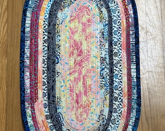 Alfombra ovalada de algodón batik (79 x 43 cm): tonos de amarillo, azul, fucsia y crema.