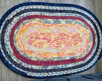 Alfombra ovalada de algodón batik (117 x 74 cm): tonos de amarillo, azul, fucsia y crema.