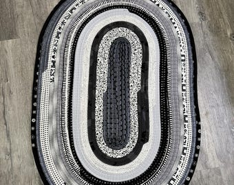 Alfombra ovalada de algodón hecha a mano (104 x 69 cm): paleta monocromática de negro, blanco y gris.