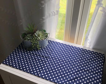 May include: A white and blue polka dot table runner on a white dresser with a small potted succulent plant.