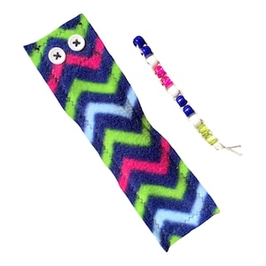 May include: A blue, green, pink, and white chevron fabric strip with two white buttons. A string of blue, white, pink, and green beads is also pictured.