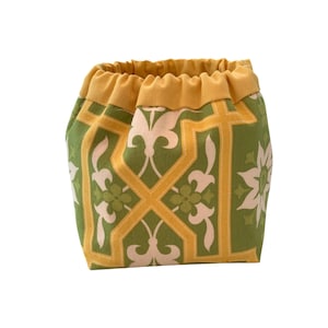 May include: A patterned drawstring bag. The bag features a green background with a repeating geometric design in yellow and off-white. The drawstring and top trim are a solid yellow. The bag is made of fabric.