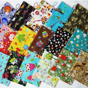 May include: A collection of quilted fabric pouches with various patterns, including sports equipment, construction vehicles, owls, and maps. Each pouch has a loop for hanging and features a variety of colors and designs.