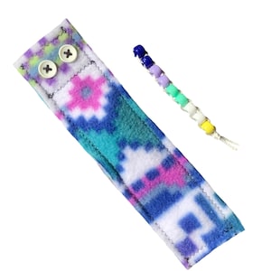 May include: A colorful fleece wristlet with two white buttons and a matching beaded bracelet with blue, purple, green, and yellow beads.