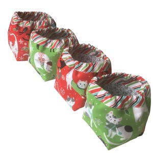 May include: Set of four green and red fabric storage bins with a Christmas cat design. The bins have a white and red striped trim.