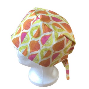 Peut inclure: Un bonnet de chirurgien à motifs avec un motif de feuilles répétées en orange, rose et jaune sur fond blanc. Le bonnet est noué dans le dos et est conçu pour couvrir la tête.