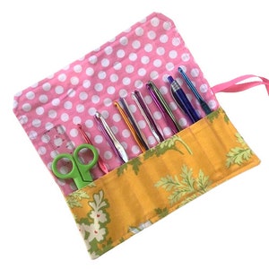 May include: A yellow and green floral fabric roll-up case with pink polka dot lining. The case holds a variety of crochet hooks, scissors, and a ruler.