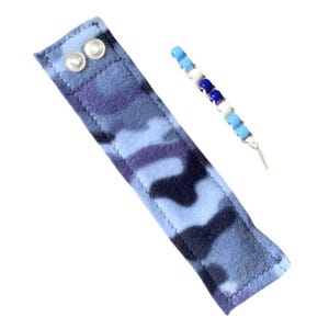May include: A blue and black camouflage fabric wristband with two white snap buttons. A beaded bracelet with blue, white, and dark blue beads is also included.