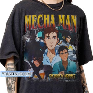 Könnte beinhalten: Dunkelgraues T-Shirt mit einem grafischen Design. Das Design zeigt den Text "MECHA MAN" in Gelb und Rot und "DISPATCH HEROES" in Gold. Die Grafik enthält Illustrationen mehrerer Charaktere in Superhelden-Kleidung.