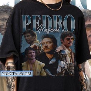 May include: Black t-shirt with a collage of images of actor Pedro Pascal. The text "PEDRO Pascal" is printed in blue and white letters on the shirt.