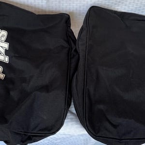 May include: Two black Ski-Doo branded bags. Each bag has the Ski-Doo logo in white, with the brand name in a stylized font. The bags appear to be made of a durable, possibly water-resistant material, suitable for outdoor gear.