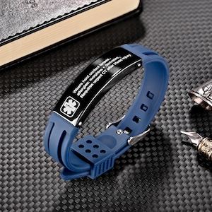 Może przedstawiać: Niebieska bransoletka medyczna z czarną metalową płytką. Płytka ma symbol medyczny i tekst: "Wears hard contact lenses, allergies: morphine + derivates, Requires urgent CT after Head Injury."