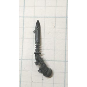 May include: A black plastic miniature sword with a detailed handle and blade. The sword is designed for use in tabletop wargaming.
