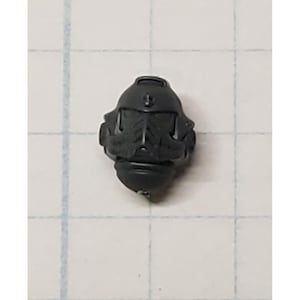 May include: Black plastic helmet with a detailed design. The helmet has a raised visor and a small, round opening for the eyes.