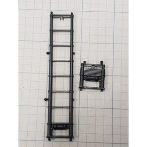 May include: A dark gray plastic model kit component consisting of a long, vertical ladder with seven rungs and a smaller, rectangular frame section featuring horizontal bars and a central cylindrical detail, both attached to a sprue frame.