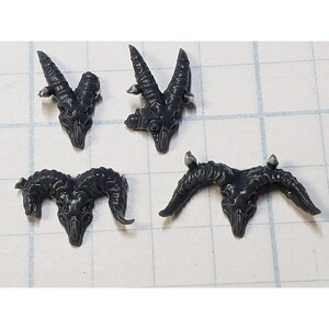 May include: Four gray plastic miniature ram skulls with horns. The skulls are in various poses, some with horns pointing up and others with horns pointing out to the sides.