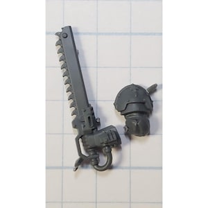 May include: A gray plastic model of a chain sword and a helmet for a miniature figure.