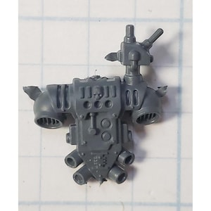 May include: Gray plastic model kit part for a sci-fi miniature. The part features a detailed design with vents, pipes, and a skull-like symbol.