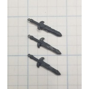 May include: Three black plastic toy swords with intricate designs. The swords have a pointed tip and a handle.