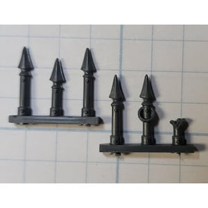 May include: A set of five gray plastic miniature fence pieces with pointed tops. The fence pieces are designed for use in tabletop games or model building.