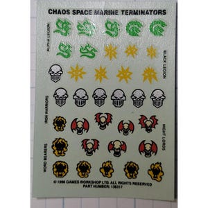 May include: A sheet of plastic decals for Warhammer 40,000 featuring various Chaos Space Marine Terminator symbols. The decals include the Alpha Legion, Black Legion, Iron Warriors, Word Bearers, and Night Lords symbols. ©1996 Games Workshop Ltd. All Rights Reserved. Part Number: 136317