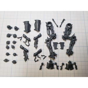 May include: A collection of unpainted gray plastic model kit components, including two large articulated mechanical leg assemblies, various small circular joints, armor plating, and intricate limb parts with cables, arranged on a grid.