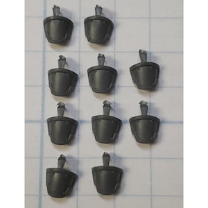May include: Ten gray plastic pieces for a model kit. The pieces are shaped like shields with a raised design.