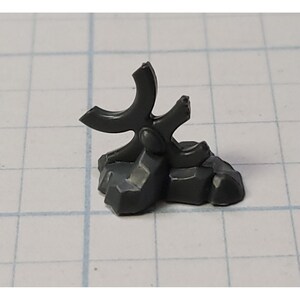 May include: A gray plastic miniature of a three-pronged star-shaped weapon on a rocky base.