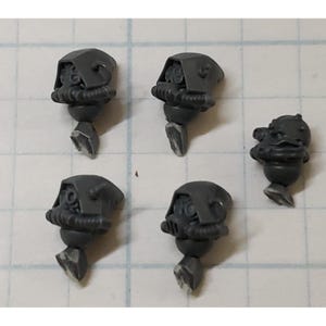 May include: Five gray plastic miniature figurines. Four figurines have a helmeted head with a respirator and a pointed base. The fifth figurine has a round head with a smiling face and a pointed base.