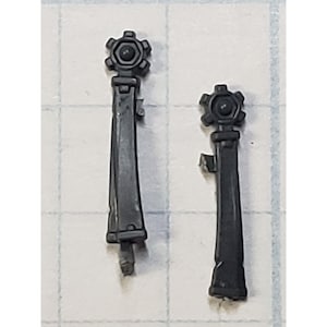 May include: Two black plastic model pieces with a star-shaped design at the top. The pieces are about 3 inches long and have a detailed design.