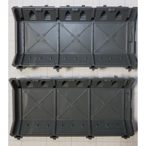 May include: Two gray plastic wall sections with a grid pattern and small rectangular openings. The sections are designed for use in a model building or miniature gaming set.