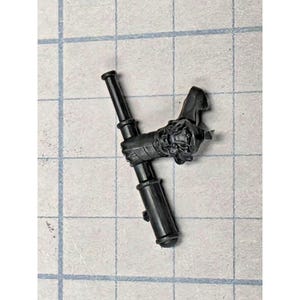 May include: A black plastic miniature component featuring a sculpted hand gripping a cylindrical baton. The hand displays detailed knuckles and wrist texture, while the baton is smooth with two distinct raised rings along its length.