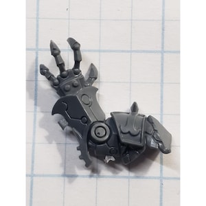 May include: A gray plastic robotic arm with articulated fingers and detailed mechanical components. The arm features a segmented design with rivets and circular joints, suggesting a futuristic or sci-fi theme.