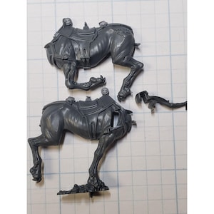 May include: Two gray plastic miniature figures of a creature with a saddle. The figures are in various stages of assembly.