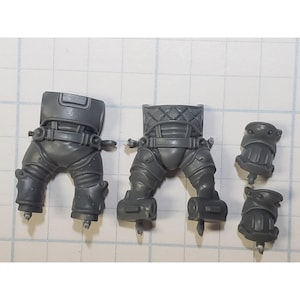 May include: Gray plastic model kit parts for a robot or action figure. The kit includes two legs, a torso, and two arms.