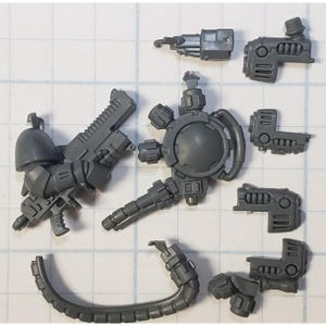 May include: A set of gray plastic miniature figures for a tabletop wargame. The figures are detailed and include weapons and accessories.