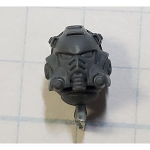 May include: Gray plastic miniature helmet with a visor and details on the side. The helmet is designed for a miniature figure.