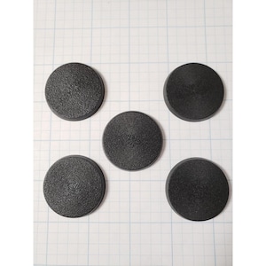 May include: Five black round plastic bases for miniature figures. The bases are textured and have a slightly raised center.
