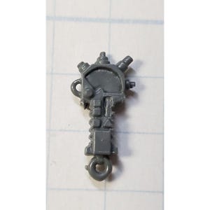 May include: A gray plastic toy weapon with a circular handle and a textured barrel. The weapon has a ring at the bottom for attaching to a figure.