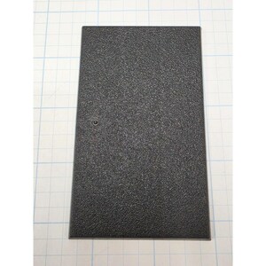 May include: A rectangular black display base with a textured, pebbled surface finish. The base features a single small, centered circular mounting hole on the left side, designed for securing a figure or object to the flat, solid platform.