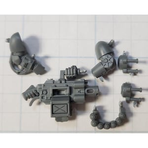 May include: A set of gray plastic miniature figures for a tabletop wargame. The figures are of a space marine with a heavy weapon and other accessories.